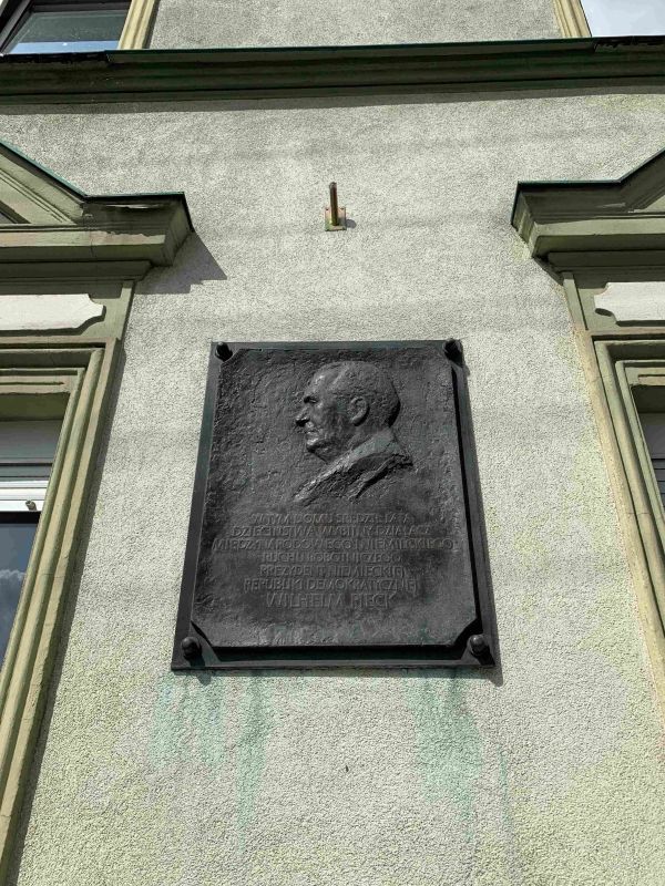 (1) Dom Wilhelma Piecka z lat dziecięcych z tablicą pamiątkową na fasadzie