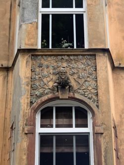 Zwei Fassadendetails des Mietshauses: eine Eule und ein Zwerg mit Kamera